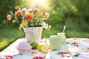 bucket of flowers sat next to a cupcake and lemonade supplies on a flower print tablecloth